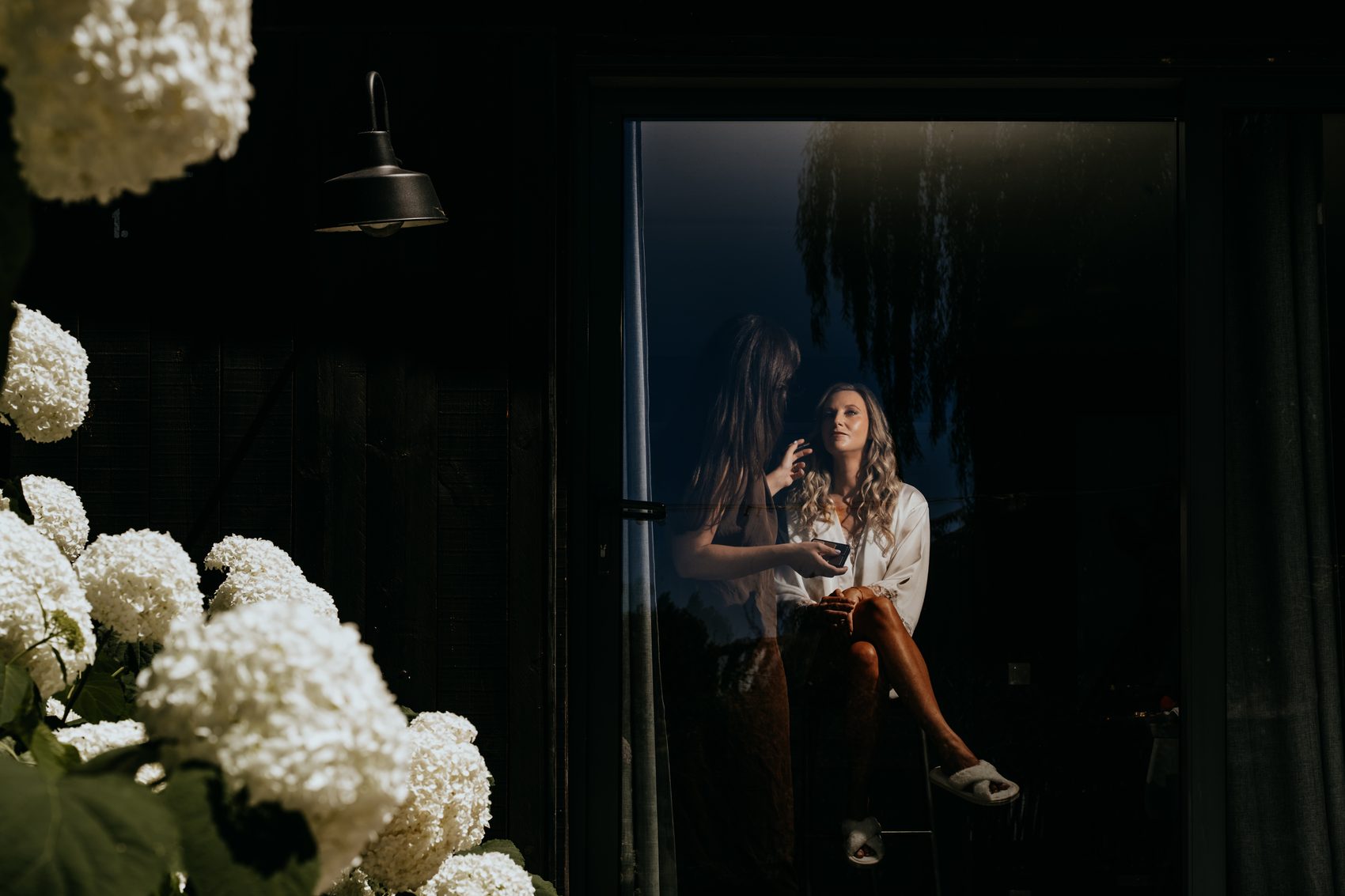 Estelle derrière la vitre, entre les hortensias