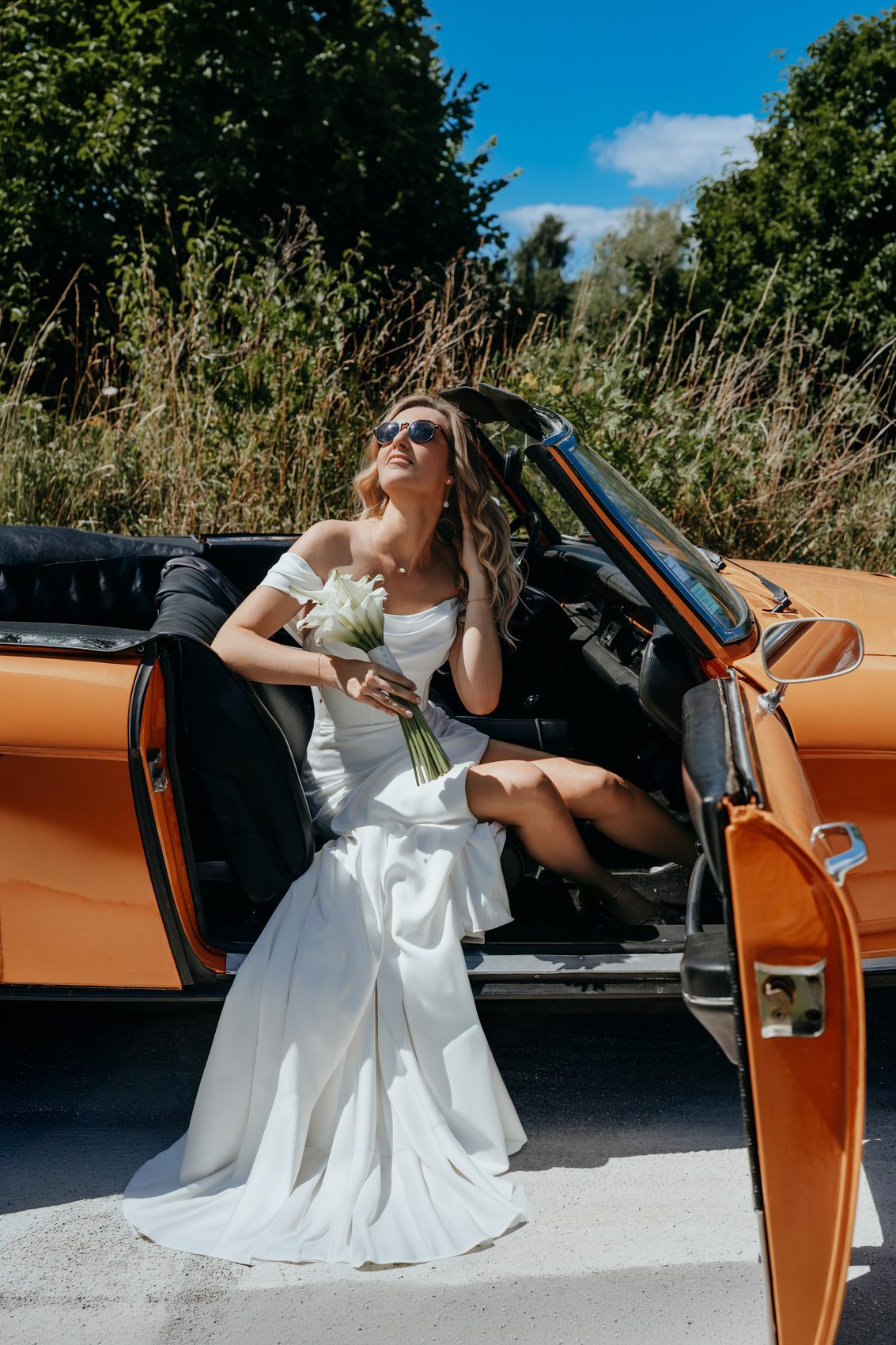 Estelle sur le cabriolet orange, bouquet à la main