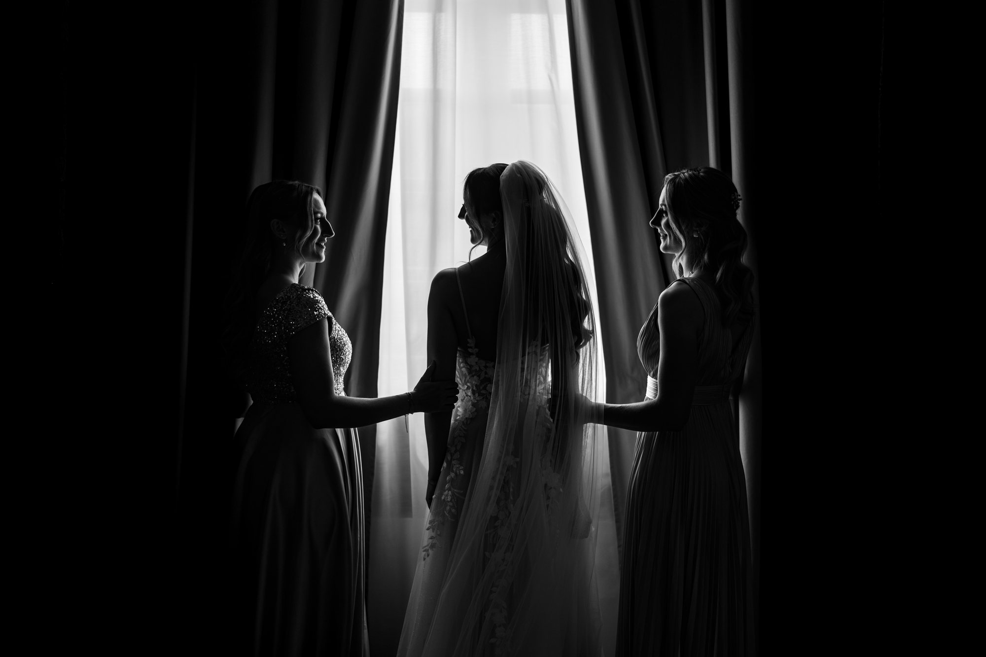 La mariée et ses témoins devant une fenêtre, en contre-jour, noir et blanc